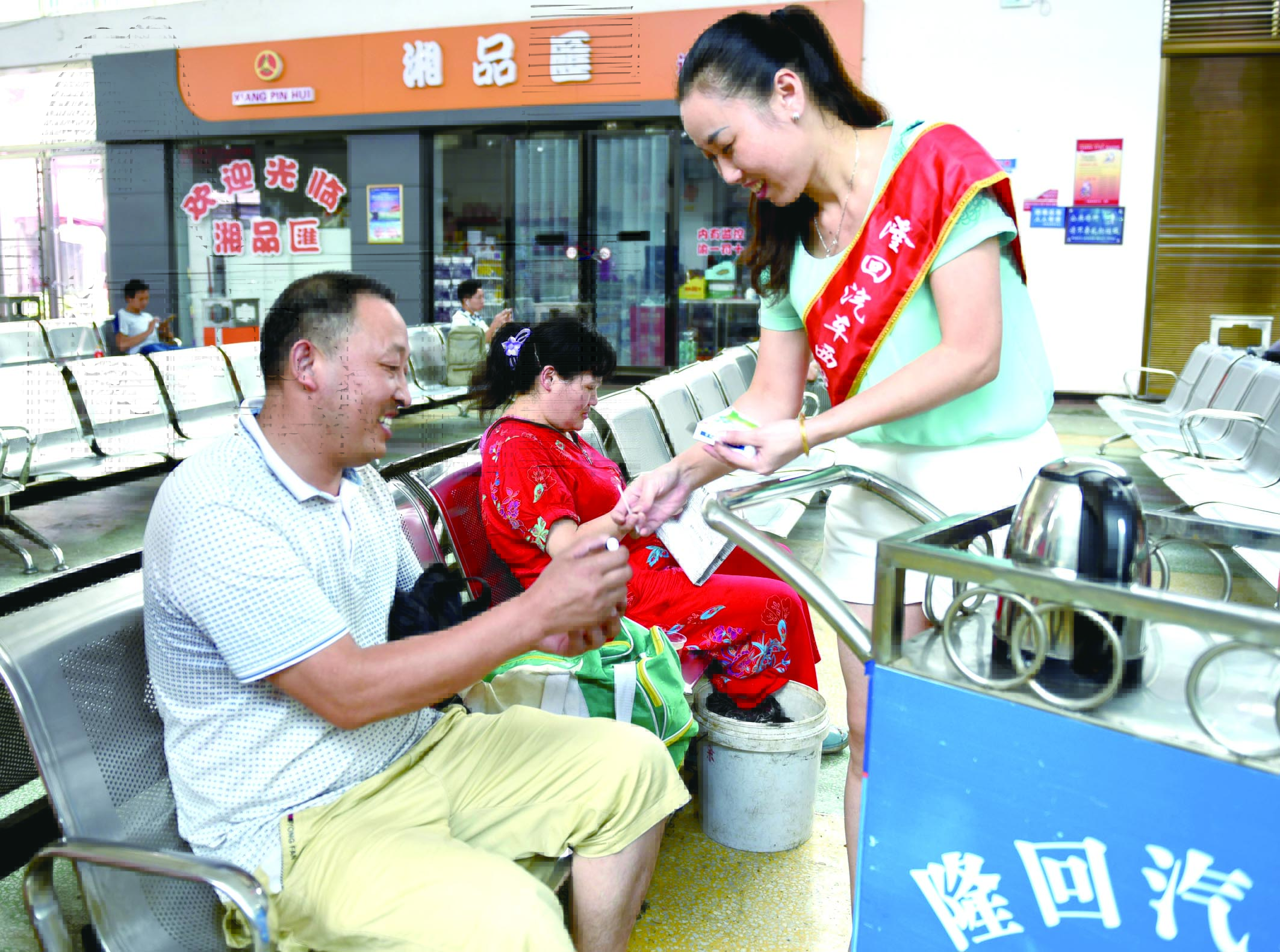 隆回分公司汽車西站工作人員正在為旅客免費(fèi)贈送藿香正氣水。